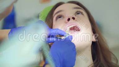 在家庭牙医治疗牙齿的女人。 牙医的双手在女人的嘴里工作